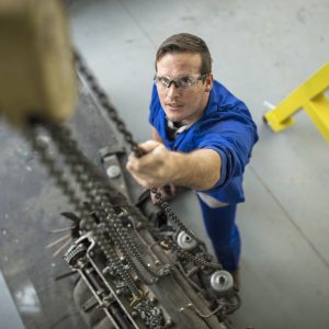 Overhead view of male car mechanic winching car engine in repair garage